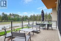 Spacious outdoor patio featuring a paver stone surface, glass panel railing, and a serene water feature backdrop - 