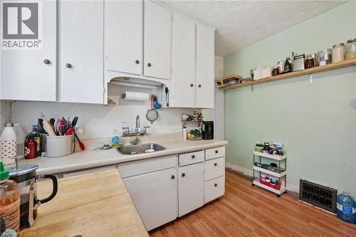 Kitchen featuring white cabinetry, a stainless steel sink, light-toned countertops, and wood-finish flooring - 95 Forest Road, Cambridge, ON - Indoor Photo Showing Kitchen