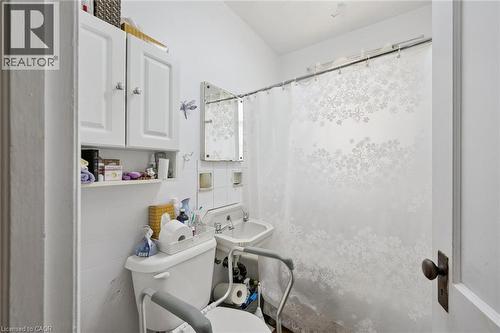 Compact bathroom featuring a wall-mounted sink, white tile backsplash, and a white toilet - 95 Forest Road, Cambridge, ON - Indoor