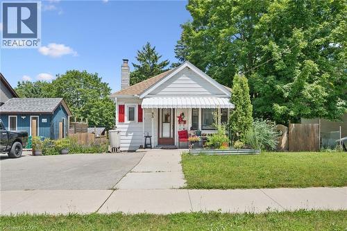 White siding exterior with red shutter accents, a front porch awning, and a prominent brick chimney - 95 Forest Road, Cambridge, ON - Outdoor