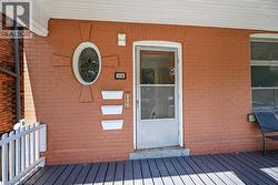 Brick facade with an oval stained-glass window, a screened entry door, and a porch featuring composite decking and a white railing - 
