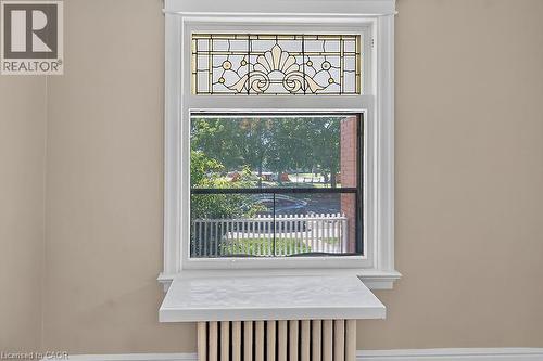 Window with decorative stained glass transom, white trim, and a white marble-look sill, situated above a fluted radiator - 103 Mary Street, Hamilton, ON - Indoor Photo Showing Other Room