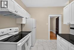 Kitchen featuring white shaker cabinetry, dark countertops, a white electric range, and a white refrigerator - 