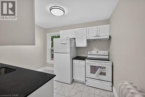 Kitchen featuring white cabinetry, dark speckled countertops, and an electric range with an overhead vent - 103 Mary Street, Hamilton, ON - Indoor Photo Showing Kitchen