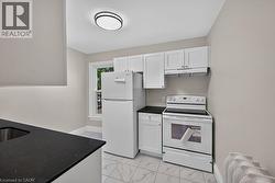 Kitchen featuring white cabinetry, dark speckled countertops, and an electric range with an overhead vent - 