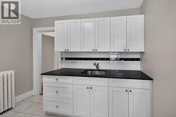 Contemporary white cabinetry with a black countertop and stainless steel sink - 