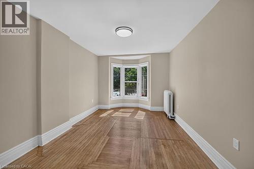 Bay window providing exterior views, neutral wall tones, wood-finish flooring, white baseboards, and a flush mount ceiling light fixture - 103 Mary Street, Hamilton, ON - Indoor Photo Showing Other Room