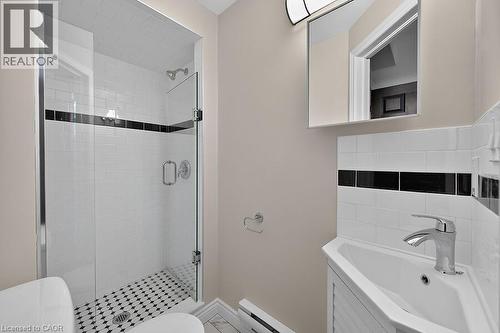 Walk-in shower featuring a glass enclosure, subway tile surround with a black accent band, and a mosaic tile floor - 103 Mary Street, Hamilton, ON - Indoor Photo Showing Bathroom