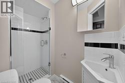 Walk-in shower featuring a glass enclosure, subway tile surround with a black accent band, and a mosaic tile floor - 
