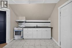 Compact kitchen area featuring white shaker-style cabinetry, dark countertops, and a subway tile backsplash with a dark accent stripe - 