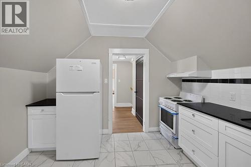 Kitchen featuring white cabinetry, dark countertops, white subway tile backsplash with a black accent, and marble-look floor tile - 103 Mary Street, Hamilton, ON - Indoor Photo Showing Kitchen
