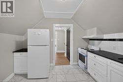 Kitchen featuring white cabinetry, dark countertops, white subway tile backsplash with a black accent, and marble-look floor tile - 