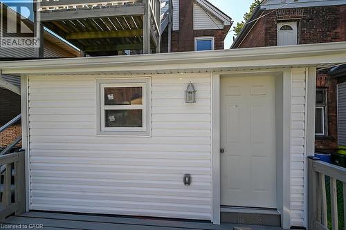 Exterior featuring white horizontal siding, a paneled door, and a window with white trim - 103 Mary Street, Hamilton, ON - Outdoor With Exterior