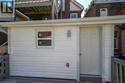 Exterior featuring white horizontal siding, a paneled door, and a window with white trim - 