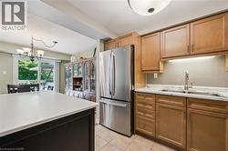 Kitchen featuring wood cabinetry, stainless steel appliances, white countertops, and a subway tile backsplash - 