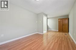 Spacious interior room featuring wood-finish flooring, light grey wall paint, and white baseboards - 