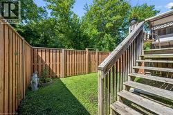 Private backyard featuring a full perimeter wood fence, lush green lawn, and a multi-level wood deck with stairs - 