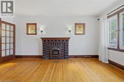 Hardwood flooring with border inlay, brick fireplace with decorative insert, stained glass window accents, and a French pane door - 
