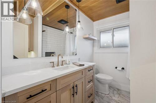 Bathroom vanity with a white countertop and light wood-finish cabinetry, featuring a built-in sink and gold-tone faucet - 223 Carter Avenue, Waterloo, ON - Indoor Photo Showing Bathroom