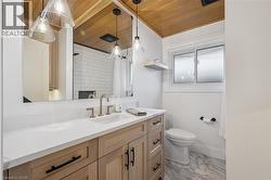 Bathroom vanity with a white countertop and light wood-finish cabinetry, featuring a built-in sink and gold-tone faucet - 