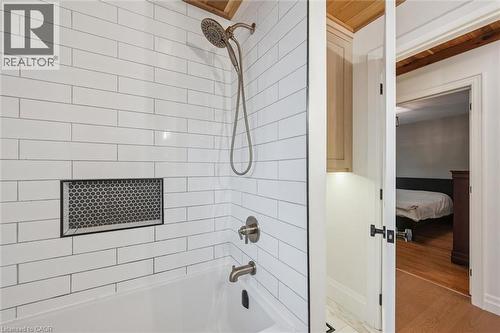 Bathtub with subway tile surround, integrated shower niche featuring penny tile, and brushed nickel fixtures - 223 Carter Avenue, Waterloo, ON - Indoor Photo Showing Bathroom