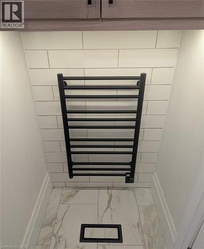 Matte black towel warmer against subway tile, complemented by wood-finish cabinetry, under-cabinet lighting, and large format tile flooring - 223 Carter Avenue, Waterloo, ON - Indoor Photo Showing Other Room