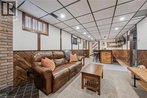 Finished entertainment area featuring wood-finish accent walls, recessed lighting, and a built-in bar with shelving - 223 Carter Avenue, Waterloo, ON - Indoor