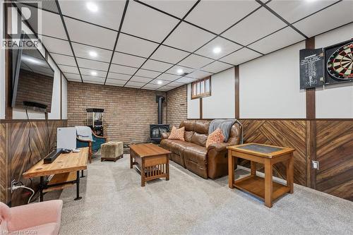 Finished basement space featuring recessed lighting, a drop ceiling, and a brick accent wall with a wood-burning stove - 223 Carter Avenue, Waterloo, ON - Indoor Photo Showing Other Room