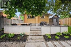 Tiered backyard patio featuring concrete steps, integrated garden beds, and a contemporary storage shed - 