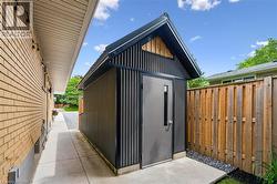 Contemporary storage shed featuring corrugated metal siding, a sloped black roofline, and a modern grey door with a vertical window - 