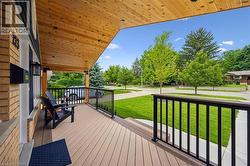 Spacious covered porch with composite decking, black metal railings, and a natural wood ceiling - 