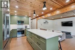 Kitchen featuring ""Eucalyptus"" green cabinetry, stainless steel appliances, a white subway tile backsplash, and a large central island with a white countertop - 