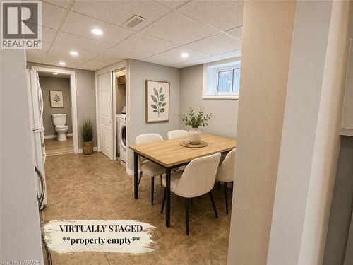 Brightly lit interior space featuring tiled flooring, a discreet laundry area with a stacked washer and dryer, and a partially visible bathroom - 90 Arlington Boulevard, Kitchener, ON - Indoor