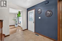 Entryway featuring a white paneled door with decorative glass, contrasting accent wall, and ceramic tile flooring - 