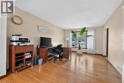 Hardwood flooring throughout a spacious room with light beige walls and a textured ceiling - 
