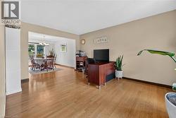 Expansive room featuring light wood-finish flooring, neutral wall tones, and a wide entryway to an additional dining area - 