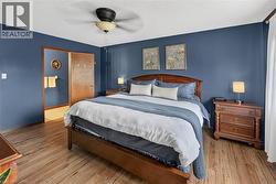 Bedroom featuring wood-finish flooring, a ceiling fan with integrated lighting, and a doorway opening to an additional room - 