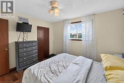 Bedroom featuring wood-finish flooring, a double-pane window, and a ceiling fan with integrated lighting - 