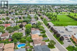 Aerial perspective of a residential neighborhood featuring diverse housing styles, mature trees, and a spacious green parkland - 