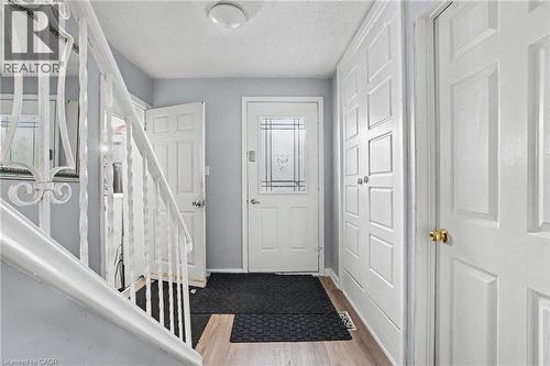 Entryway featuring wood-finish flooring, a white paneled front door with decorative glass inserts, and an iron baluster staircase - 47 Bowman Street, Hamilton, ON - Indoor Photo Showing Other Room
