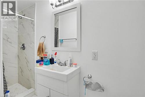 Bathroom featuring a white vanity with integrated sink, chrome faucet, and a wall-mounted mirror with an overhead light fixture - 47 Bowman Street, Hamilton, ON - Indoor Photo Showing Bathroom