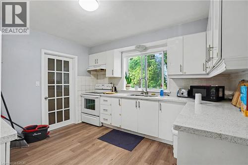 Kitchen featuring wood-finish flooring, white cabinetry with modern hardware, and light-colored countertops - 47 Bowman Street, Hamilton, ON - Indoor Photo Showing Kitchen With Double Sink