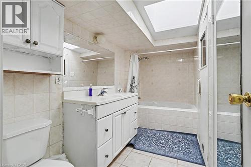 Bathroom featuring a vanity with integrated sink, white cabinetry, overhead storage, tiled walls, and a skylight - 47 Bowman Street, Hamilton, ON - Indoor Photo Showing Bathroom