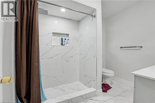 Shower enclosure featuring white marble-look tile walls and floor, a built-in shower niche, and a recessed ceiling light - 47 Bowman Street, Hamilton, ON - Indoor Photo Showing Bathroom