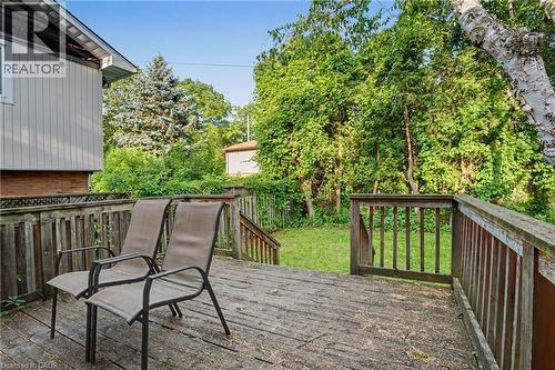 Spacious wood deck with a full-height railing system, offering access to a grassy yard bordered by mature trees and natural foliage - 47 Bowman Street, Hamilton, ON - Outdoor
