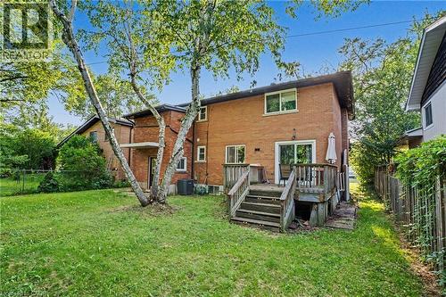 Expansive grassy backyard featuring a multi-level wood deck with stairs, brick exterior, and mature trees - 47 Bowman Street, Hamilton, ON - Outdoor