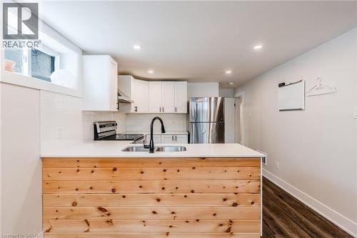 Modern kitchen featuring a wood-panel island with a white countertop and an undermount sink with a matte black faucet - 16 Ronaldshay Avenue, Hamilton, ON - Indoor Photo Showing Kitchen With Double Sink