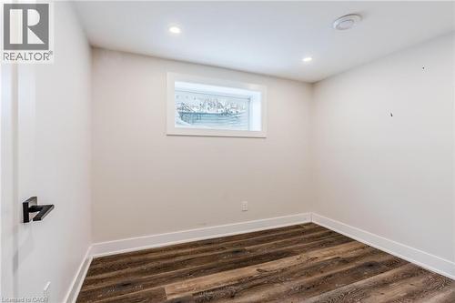 Room featuring wood-finish flooring, recessed lighting, and a white egress window - 16 Ronaldshay Avenue, Hamilton, ON - Indoor Photo Showing Other Room