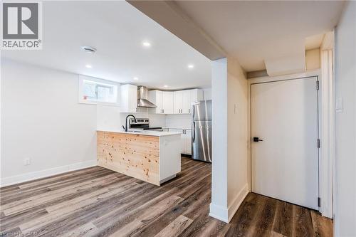 Modern kitchen featuring white cabinetry, stainless steel appliances, and a central island with a wood-finish panel - 16 Ronaldshay Avenue, Hamilton, ON - Indoor Photo Showing Kitchen
