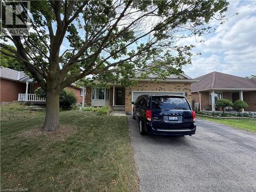 Brick exterior featuring an attached garage, a paved driveway, and a front lawn with mature trees - 436 Gatestone Boulevard, Waterloo, ON - Outdoor